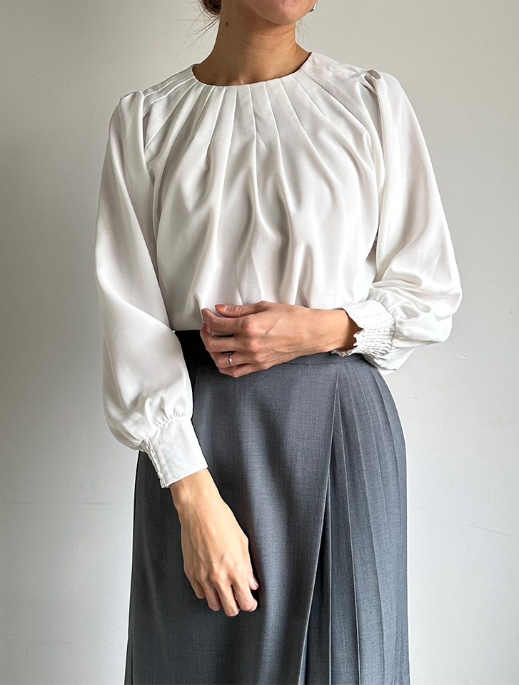 フロントタックプリーツブラウスの白とグレーのスカートを合わせた、清潔感のある春のレディース・オフィスカジュアル